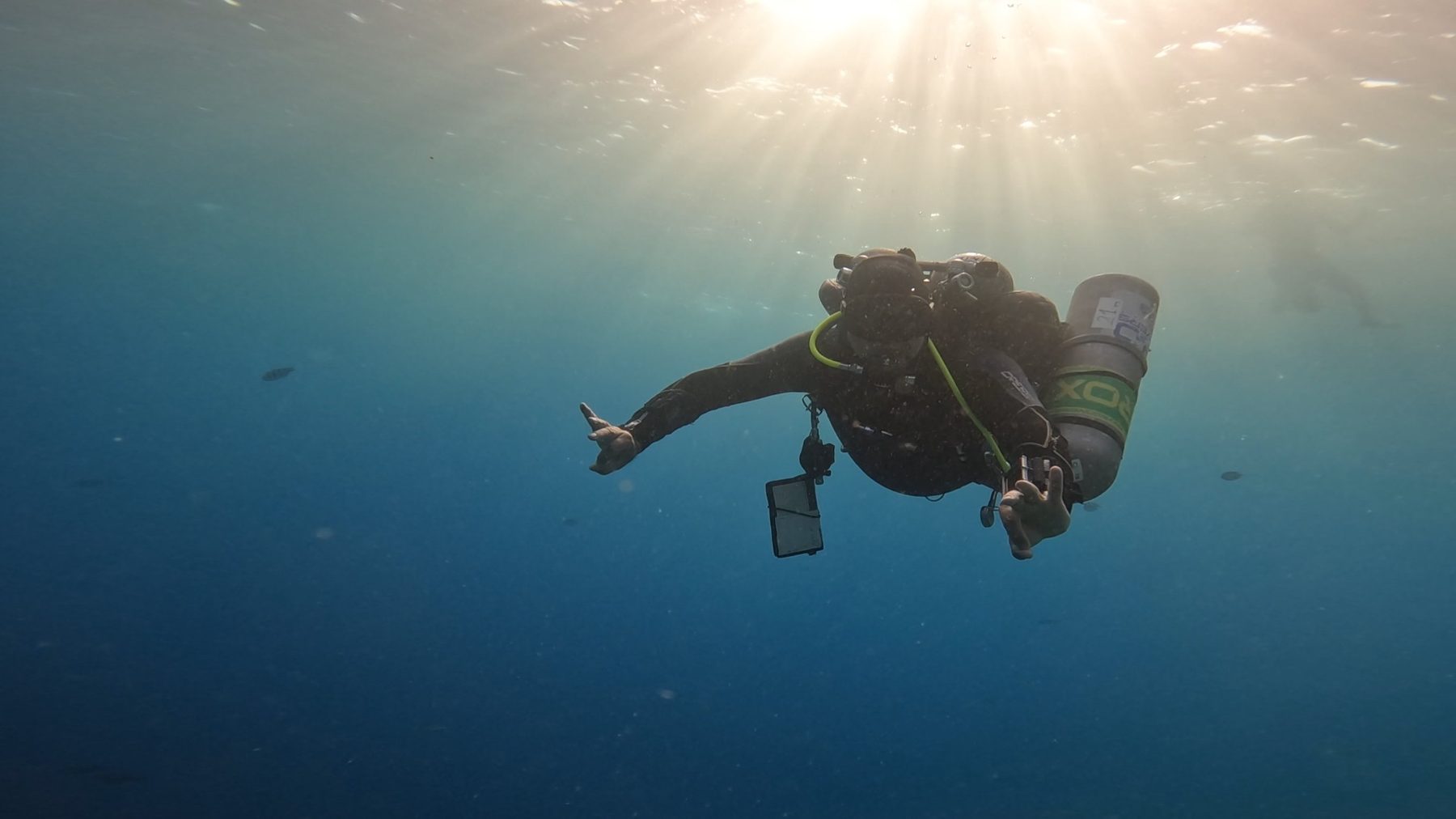Technikai búvár sidemount felszerelésben napsugarak között a nyílt tengerben